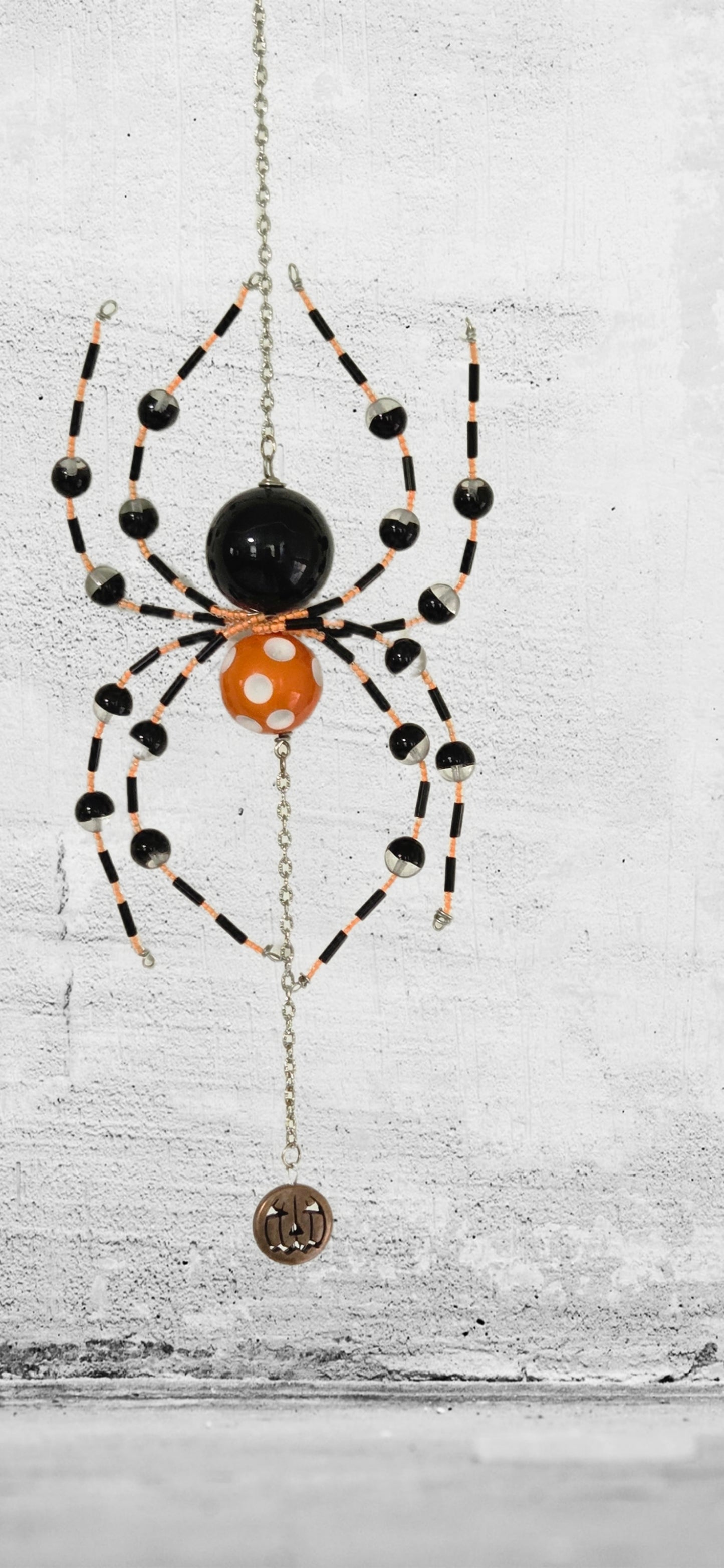 Add a little spooky charm to your space with this handmade beaded spider hanging,
Designed with classic Halloween colors, this piece features black, orange, and white beaded legs, a bold spider body, and a dangling pumpkin-style charm for an extra festive touch.
Perfect for Halloween decorating, gothic-inspired rooms, covered porch displays, office decor, or as a unique seasonal gift, this hanging spider brings playful personality wherever it’s displayed. Each piece is handmade, so